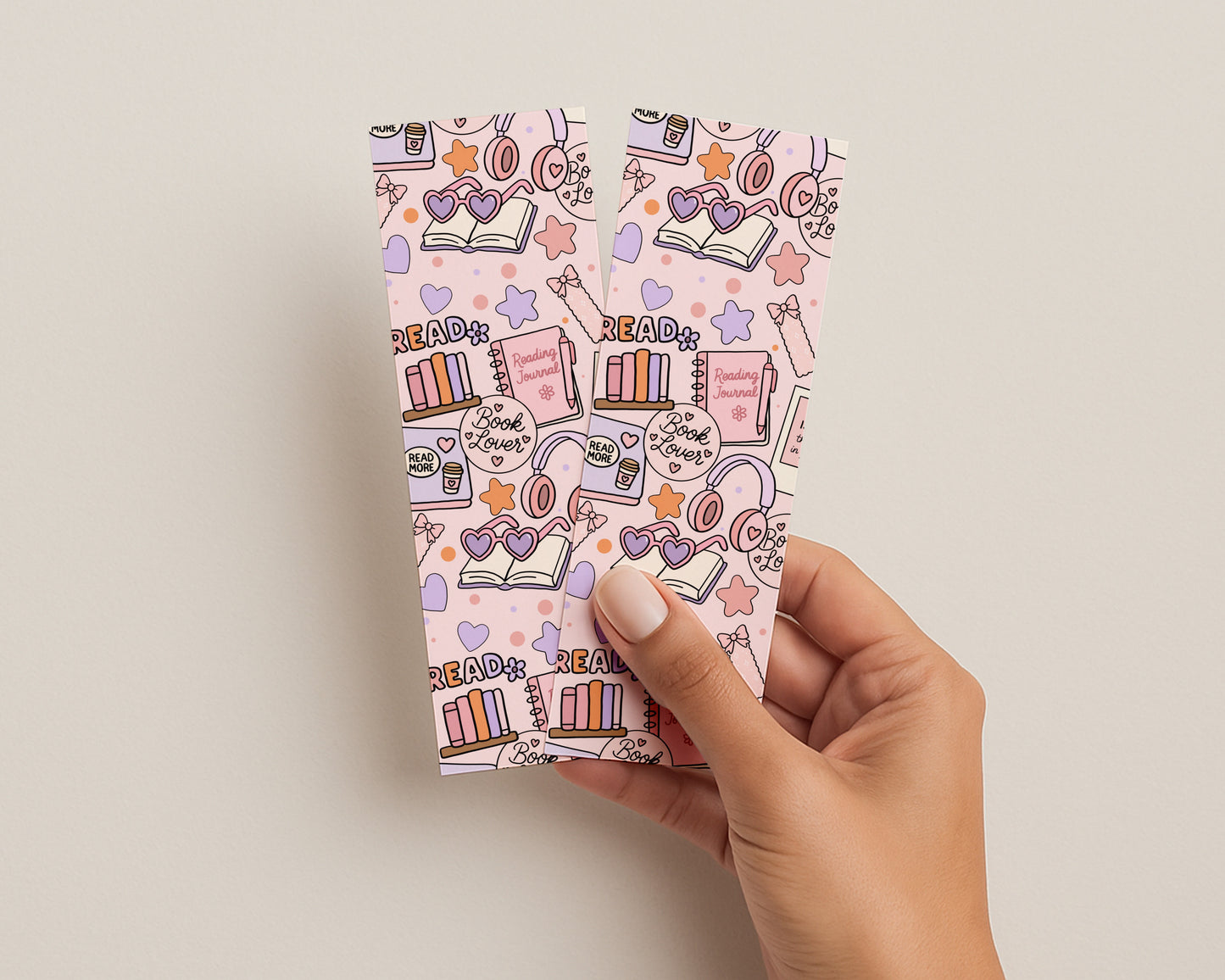 Hand holding bookmarks with colorful book-themed design on a beige background