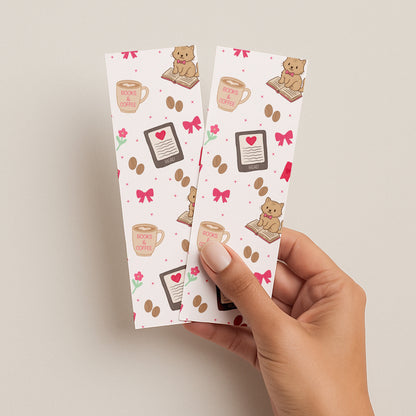 Two bookmarks with cats and coffee design held by a hand on a beige background