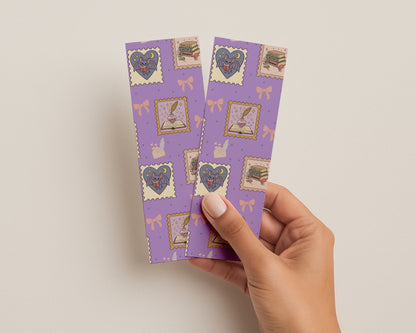 Hand holding purple bookmarks with romantasy decorative stamps on a light background