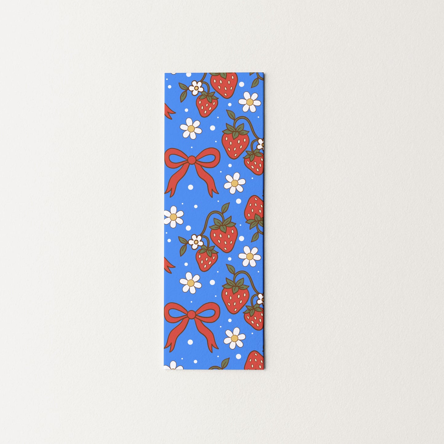 Rectangular blue bookmark with strawberry and bow pattern on a light gray background