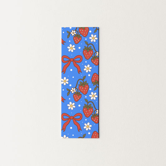 Rectangular blue bookmark with strawberry and bow pattern on a light gray background