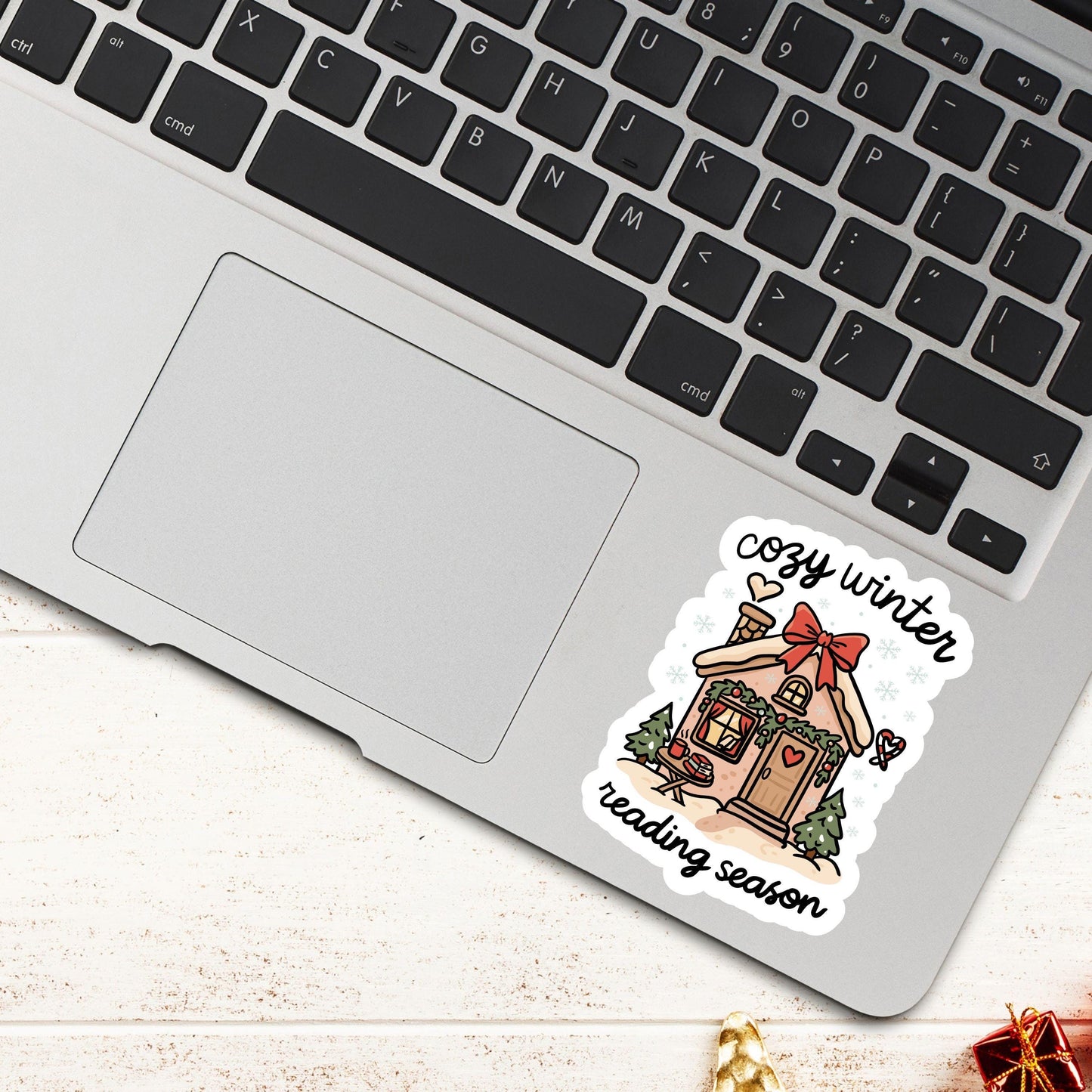 Laptop decorated with cozy winter reading season gingerbread cottage sticker surrounded by winter holiday accents.