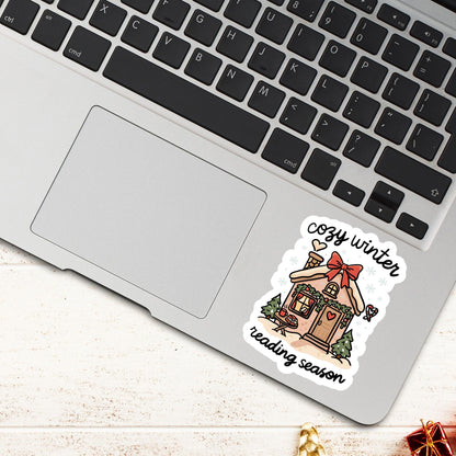 Laptop decorated with cozy winter reading season gingerbread cottage sticker surrounded by winter holiday accents.