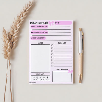 daily gratitude daily planner notepad on plain background with pen and plant