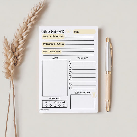 daily planner yellow and white a5 on plain background with pen and fake plant