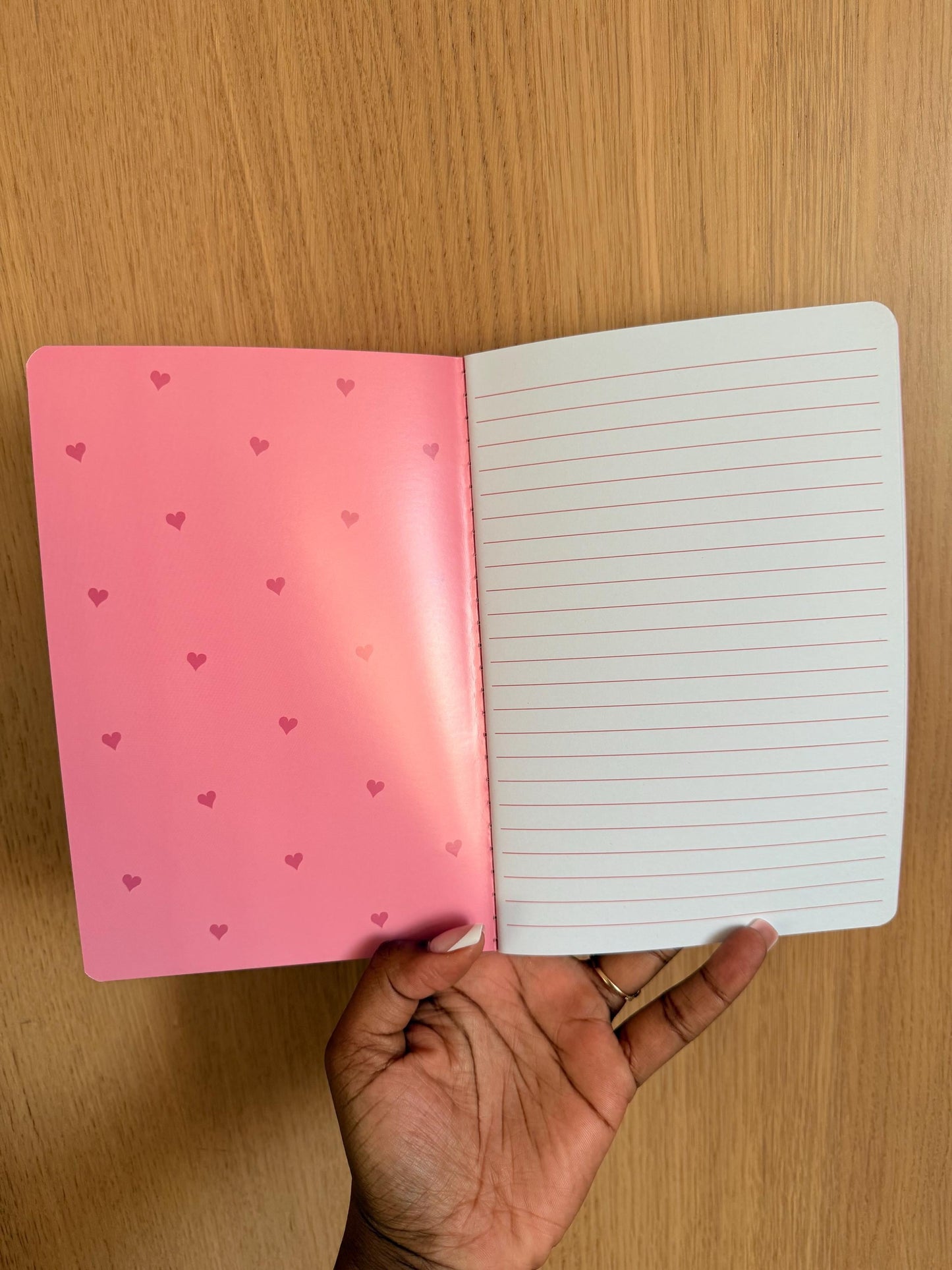 Notebook opened to show lined interior pages with a soft pink inside cover.