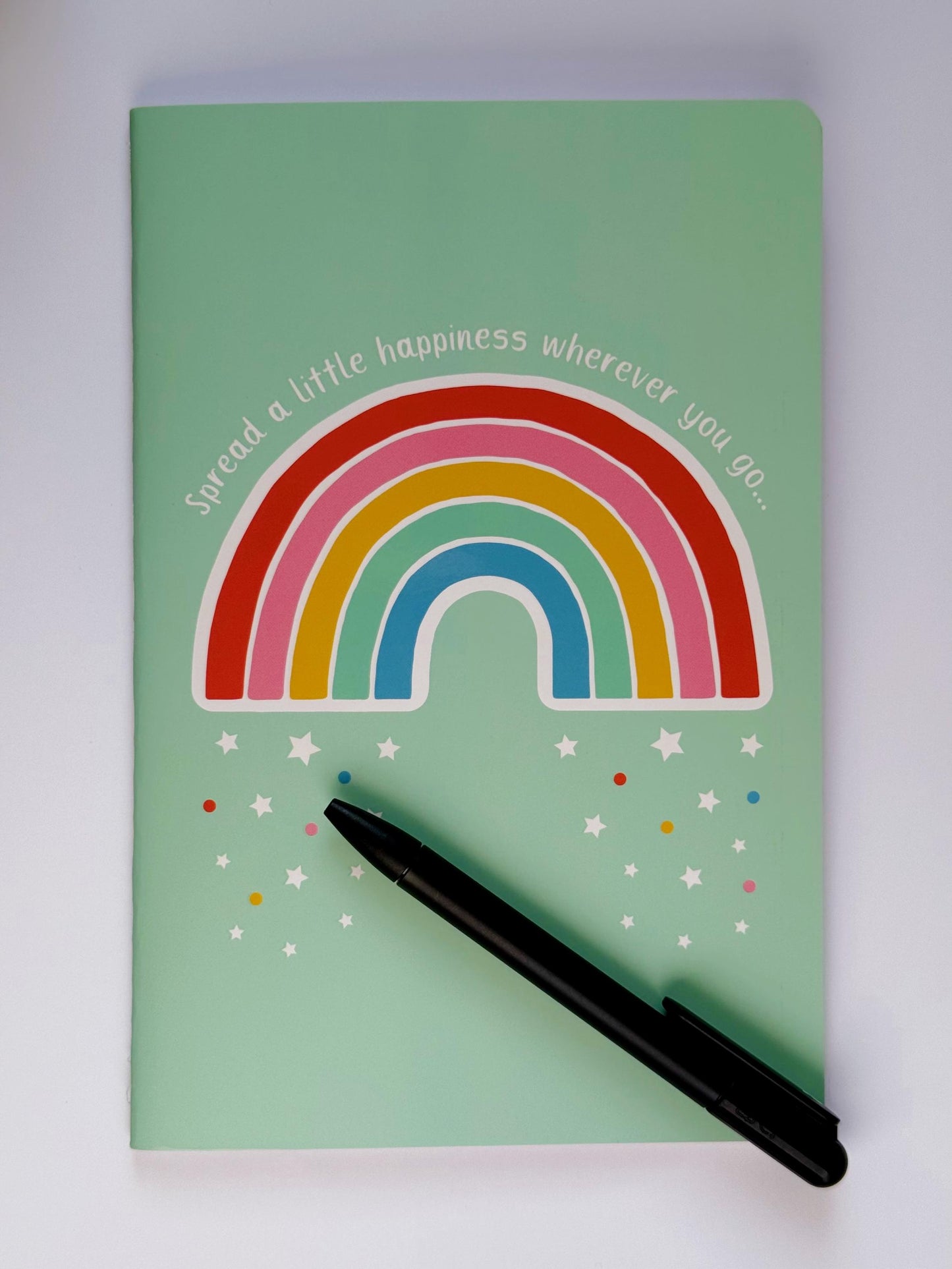 Rainbow notebook with a pen placed on top to show everyday writing use and size.