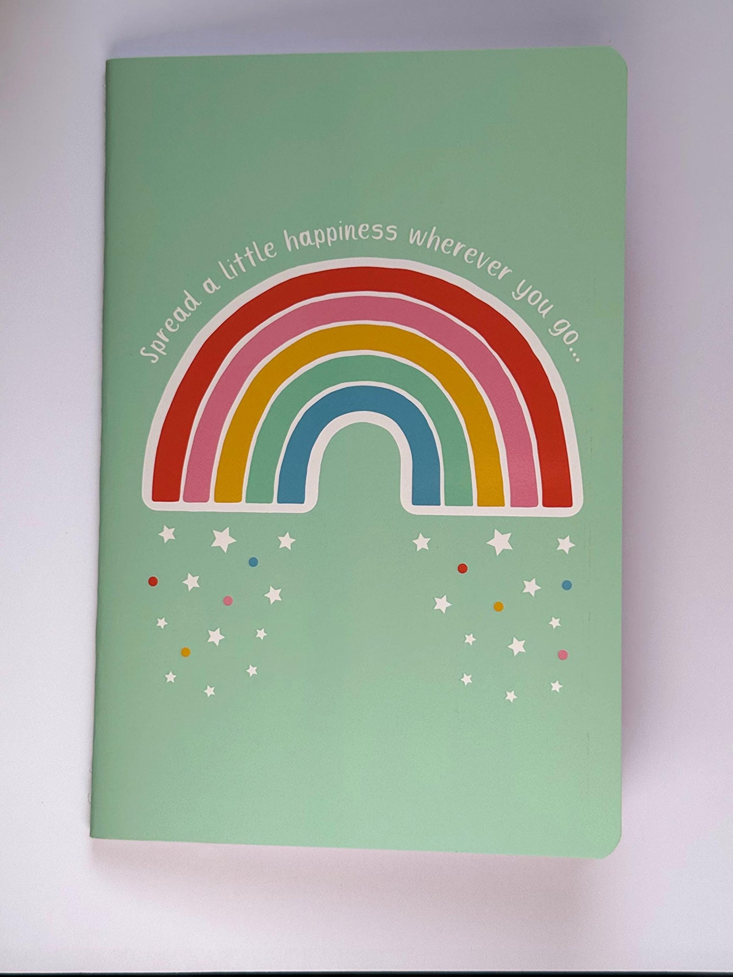 Front view of the rainbow notebook showing the full cover design with bright rainbow arches and confetti details.