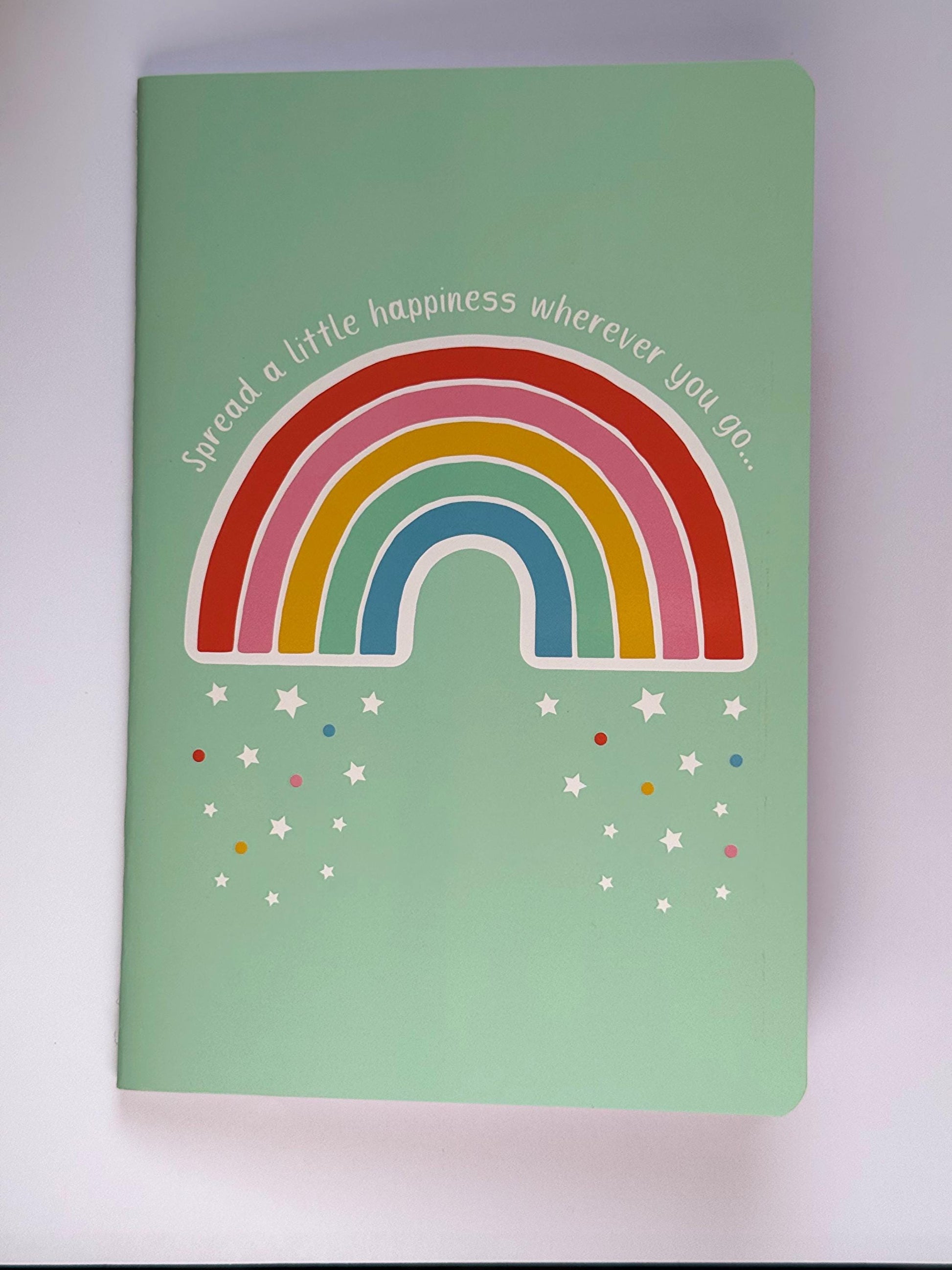 Front view of the rainbow notebook showing the full cover design with bright rainbow arches and confetti details.