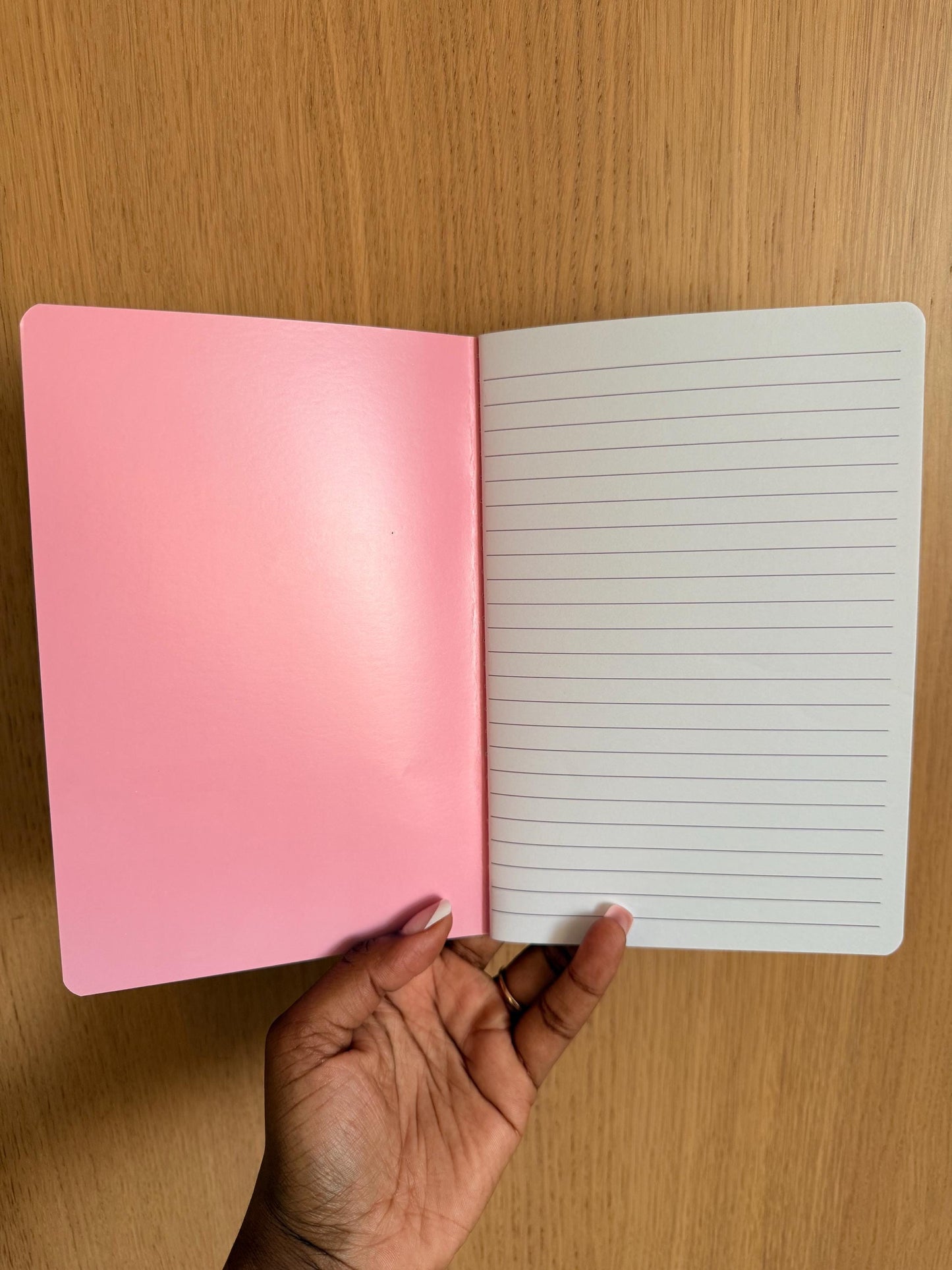Notebook opened to show lined interior pages with a pink inside cover.