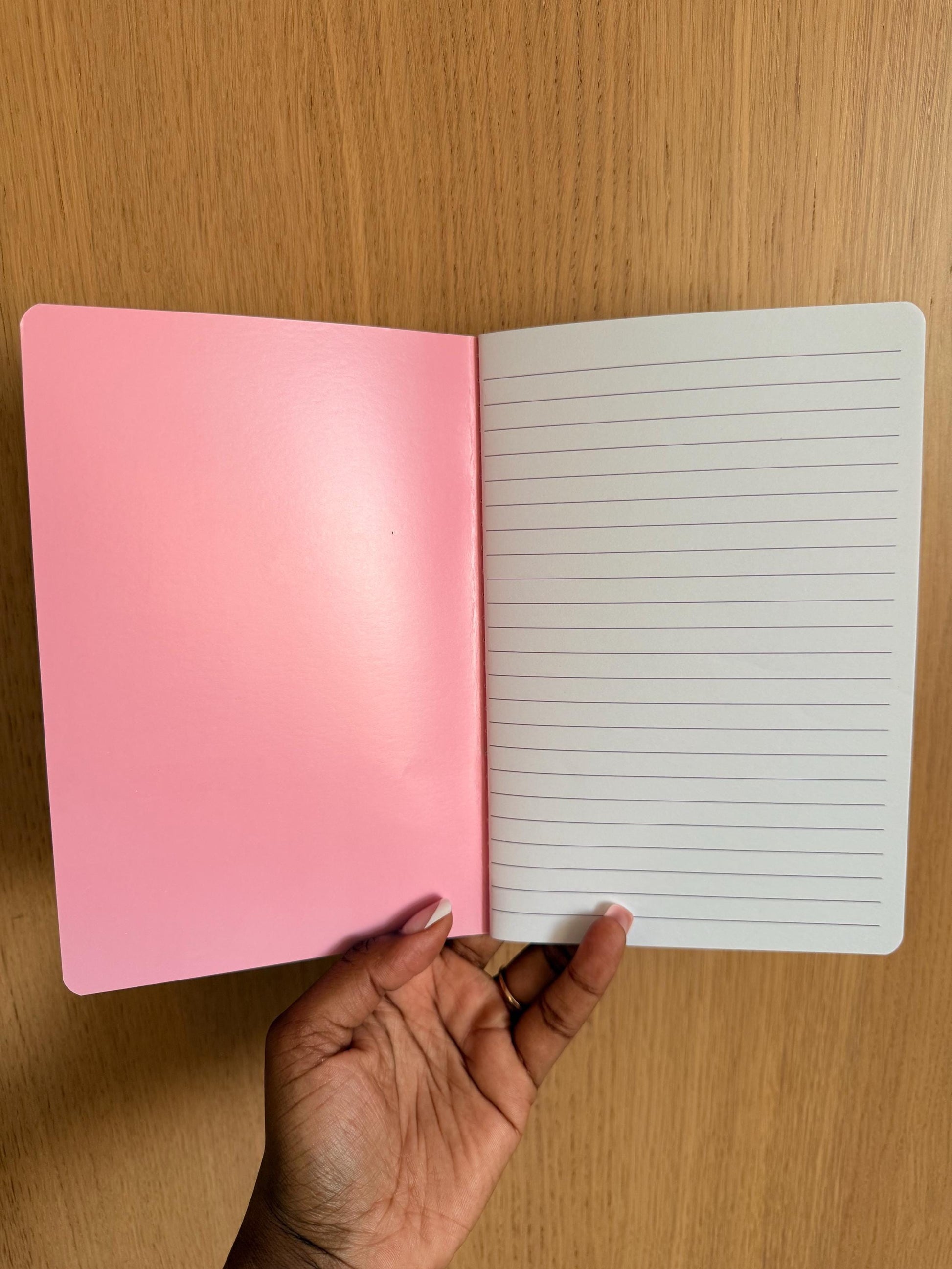 Notebook opened to show lined interior pages with a pink inside cover.